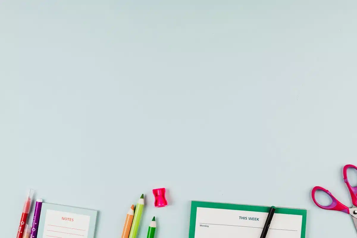 Fournitures scolaires et cahier ouvert sur un bureau avec un sac à dos