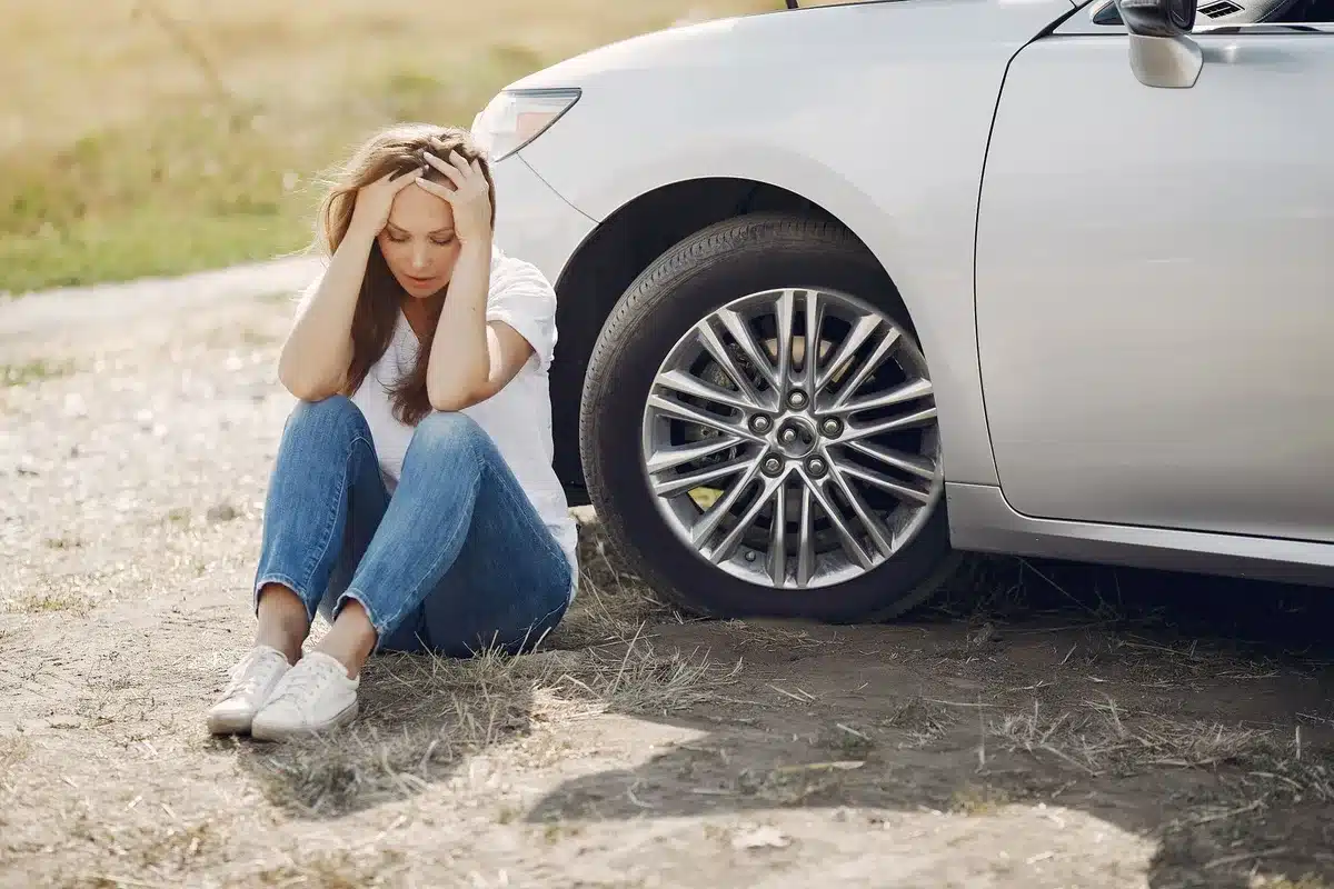 Person standing near damaged vehicle after a minor accident, showing stress and concern.