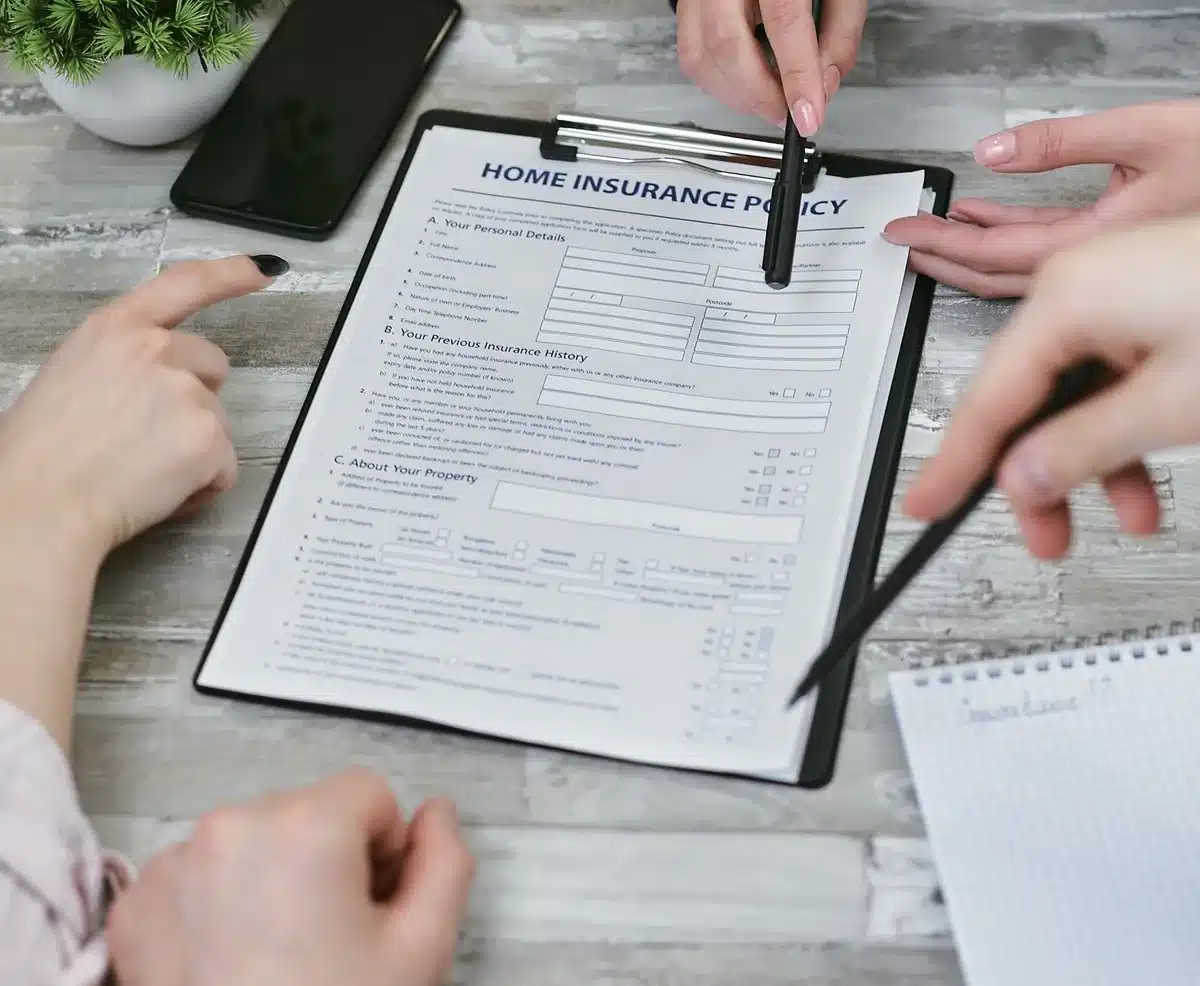 Hands reviewing insurance documents and claim forms on a desk.