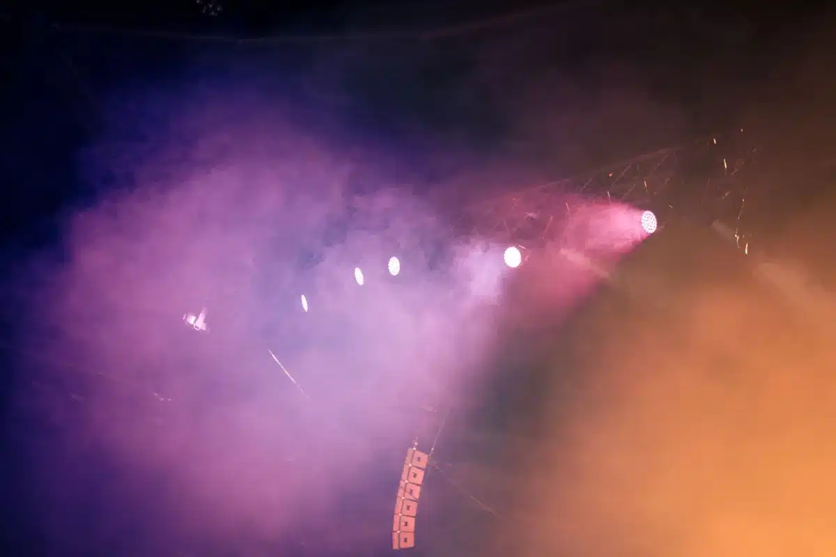 Dimly lit concert stage with warm lighting and empty microphone stand, honoring a musical legacy