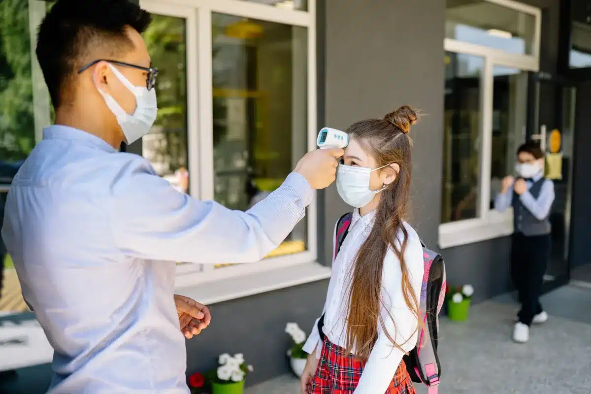 Un enfant tenant la main d'un parent devant l'entrée d'une école élémentaire