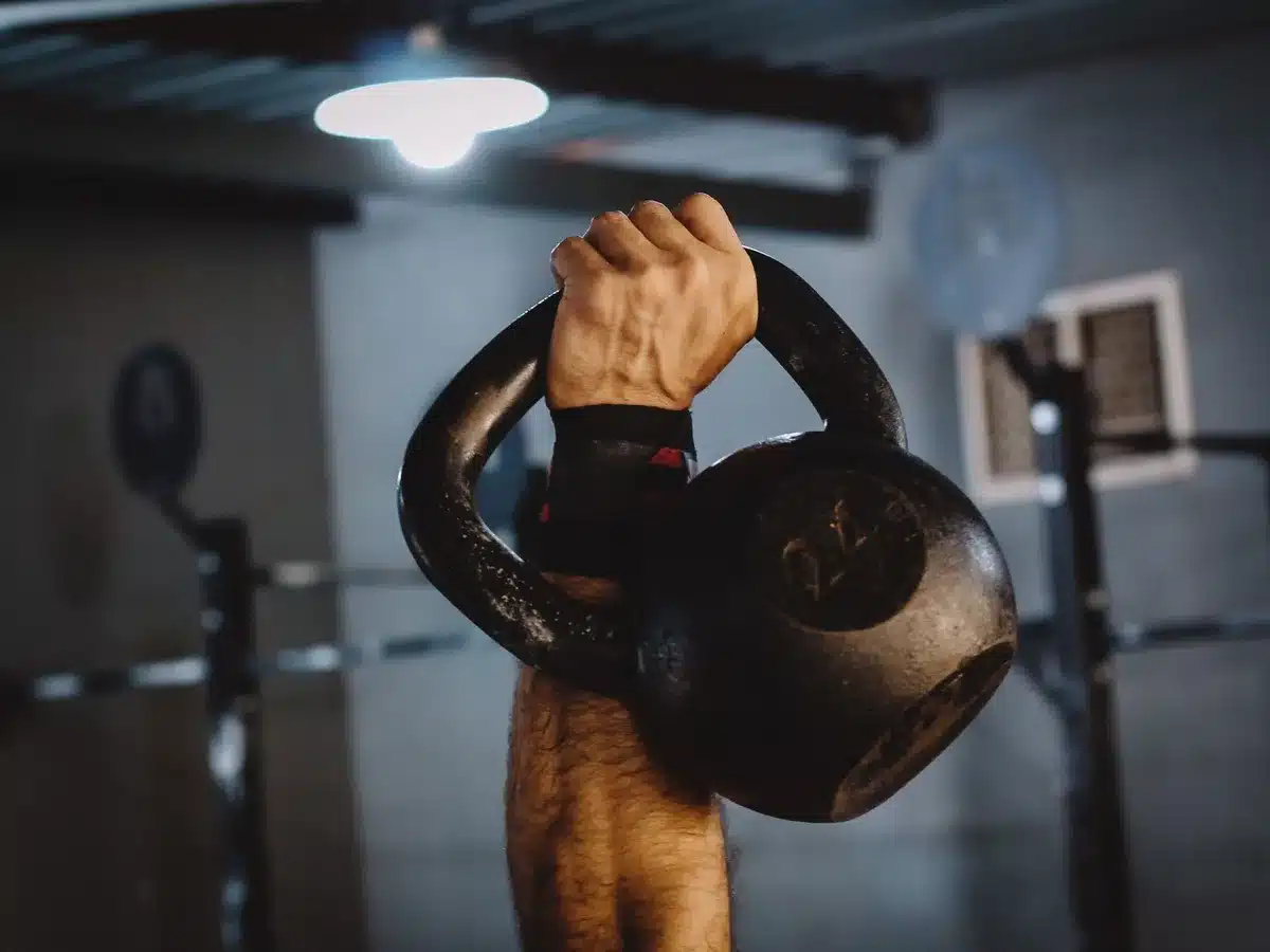 Person performing a kettlebell swing exercise in a home gym environment