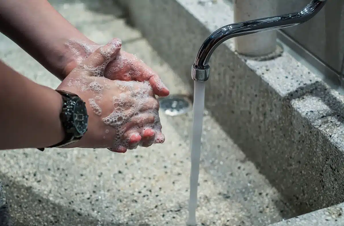 Person rinsing hair with clean fresh water under a shower head