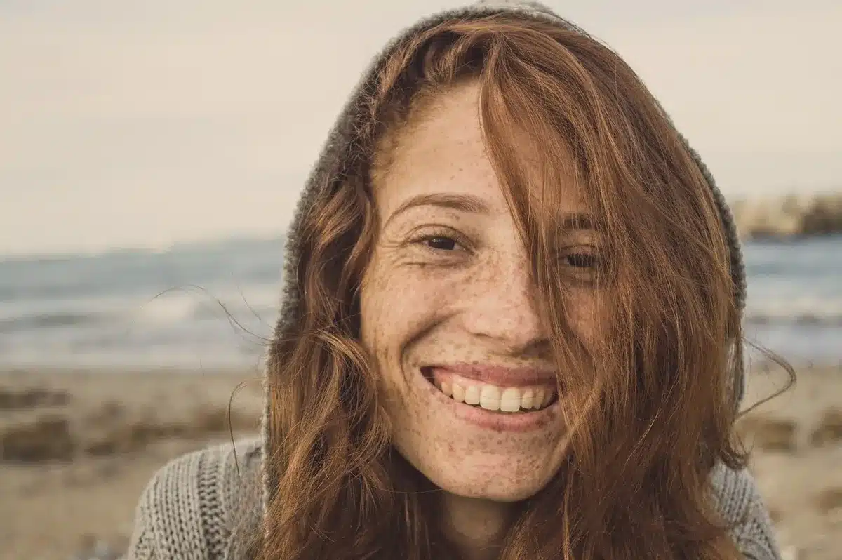 Person rinsing wet hair with fresh water before swimming in the ocean on a sunny beach day