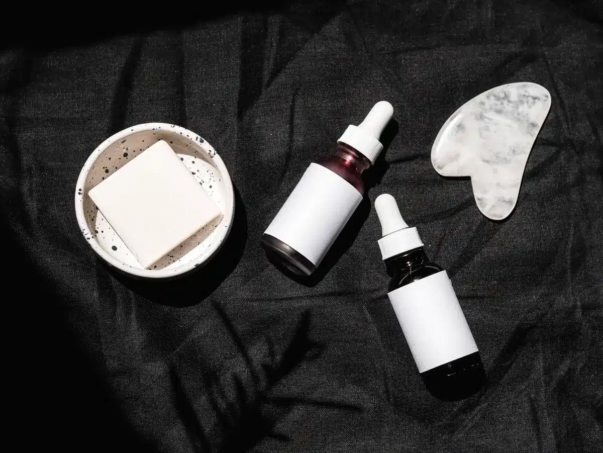 Various unmarked hair care bottles and serums on a surface with a magnifying glass