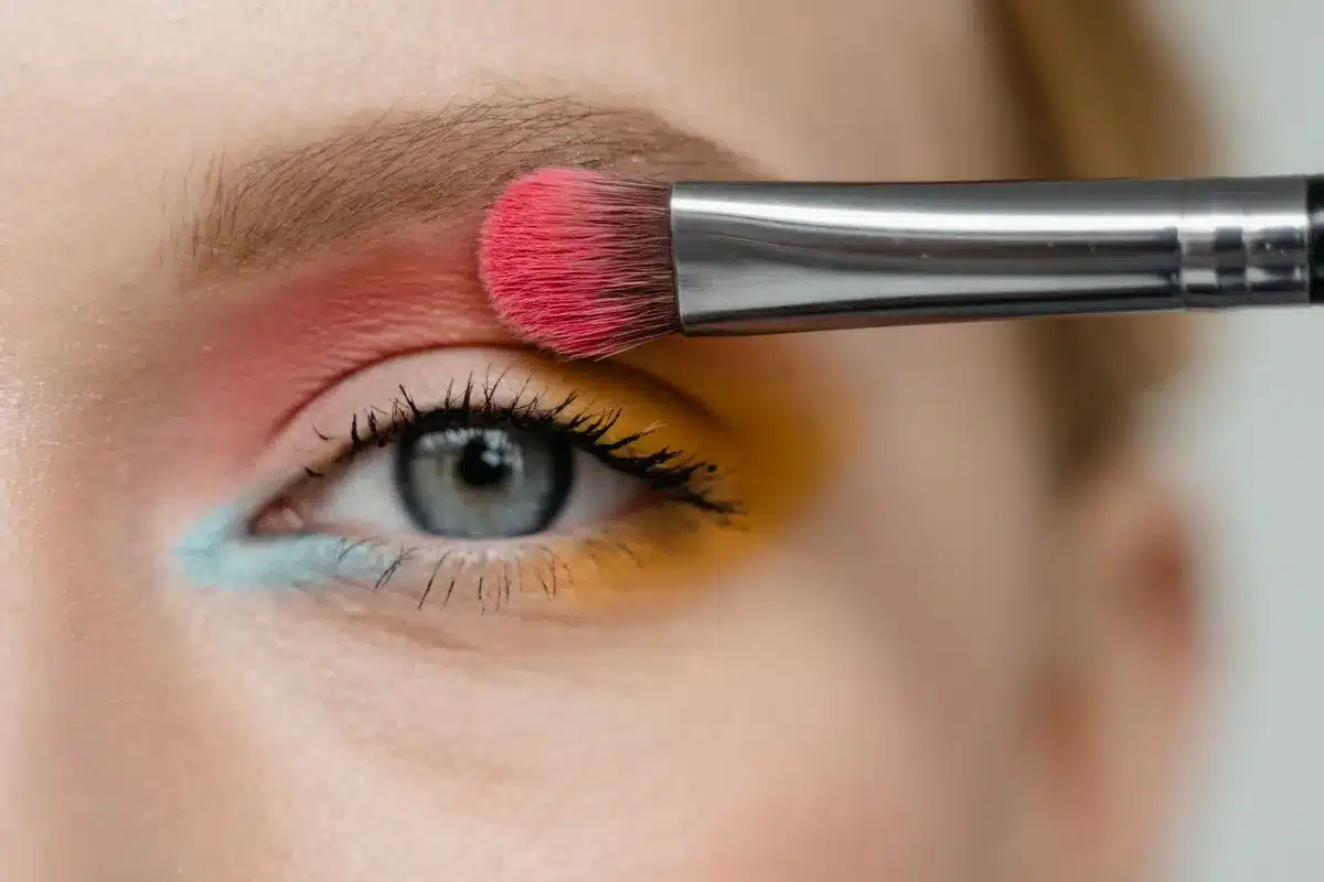 A black eyeshadow palette being applied with a brush for eyeliner look