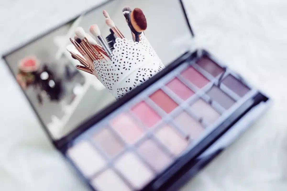 A beauty vanity setup with makeup, skincare, and styling tools arranged on a surface near a lit mirror