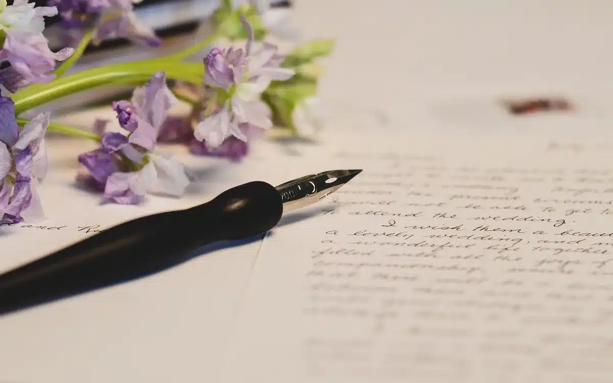 Mains tenant un journal de prénoms ouvert avec des notes écrites à la main sous une lumière douce.