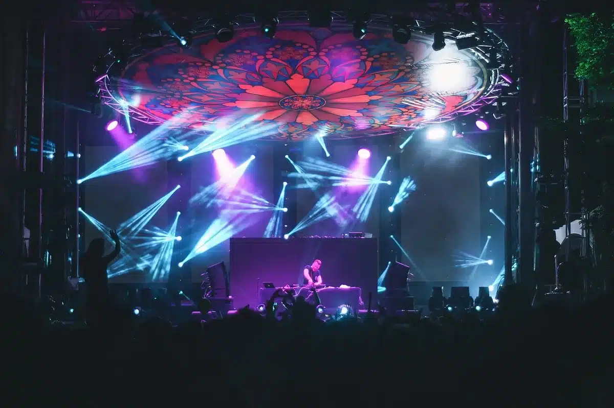A brightly lit dance floor on a television stage with spotlights and an audience in the background.