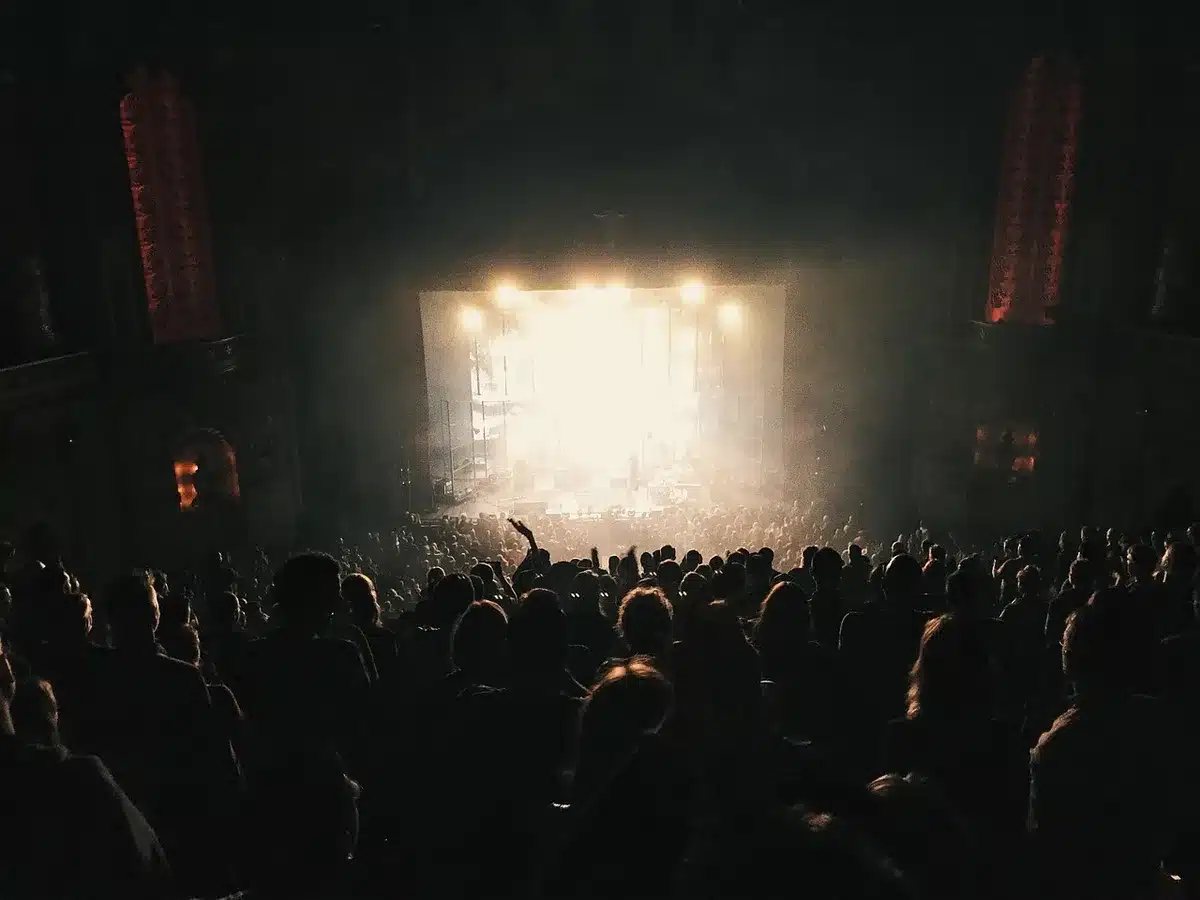 Anonymous crowd at an award-style party with a small stage and decorative kettle prop