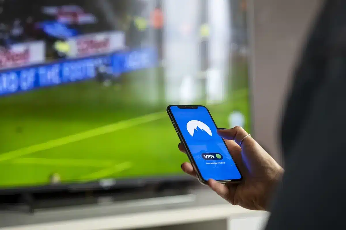 A person watching live sports on a television screen at home with streaming service displayed.