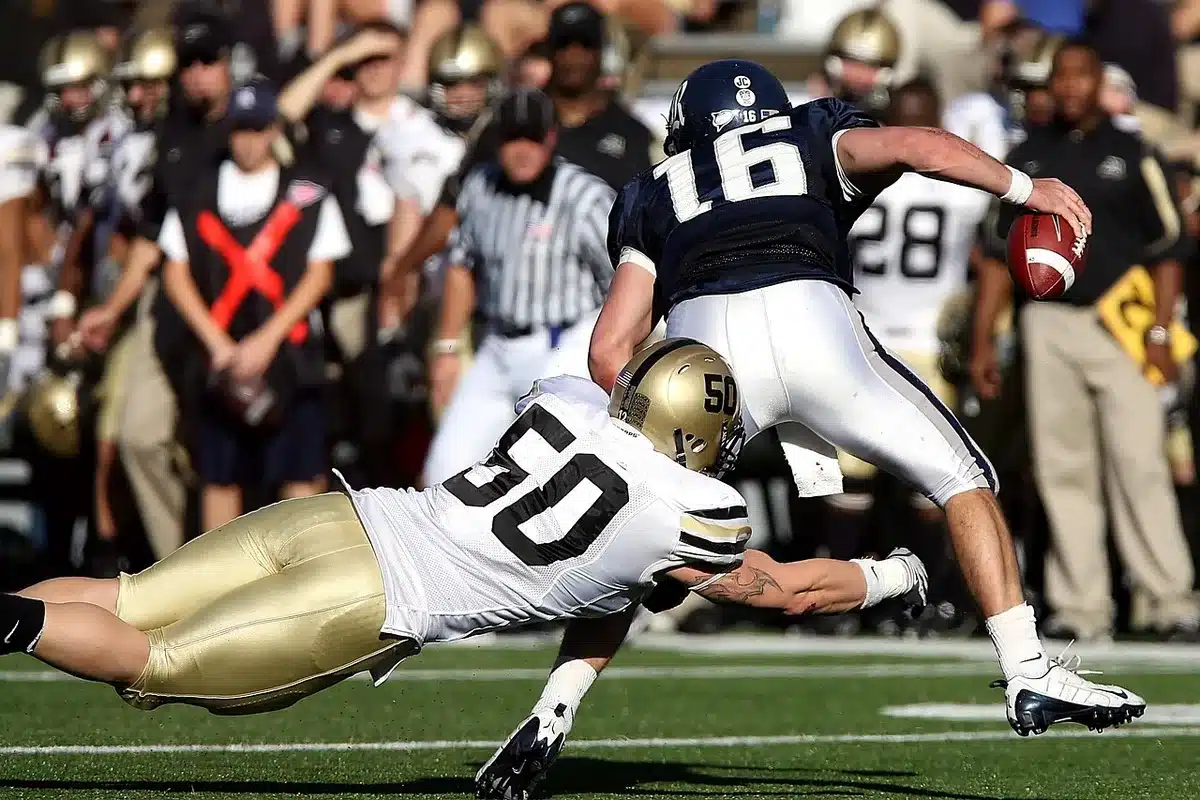 College football quarterback in uniform on sideline during game